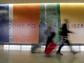 Travelers walk with their luggage after exiting the customs and immigration area at the international arrivals terminal at Newark Liberty International Airport, Thursday, Oct. 26, 2017, in Newark, N.J. Long-haul carriers are starting new screening procedures for U.S.-bound passengers after receiving new security guidelines from American authorities. (AP Photo/Julio Cortez)