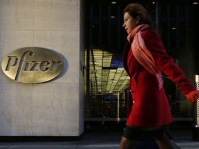 FILE - In this Monday, Nov. 23, 2015, file photo, a woman passes Pfizer's world headquarters in New York. Pfizer Inc. reports earnings Tuesday, Oct. 31, 2017. (AP Photo/Mark Lennihan, File)