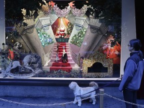 FILE - In this Nov. 18, 2013, file photo, a woman walks her dog past a vintage Santa Claus holiday window display at Lord & Taylor department store in New York. A real estate startup called WeWork Cos. is announcing a deal to buy Lord & Taylor's storied flagship in Manhattan for $850 million. The transaction, announced Tuesday, Oct. 24, 2017, is part of an overall plan by Lord & Taylor's parent Hudson's Bay Co. to pare down its debt and reinvigorate the chain. (AP Photo/Mark Lennihan, File)