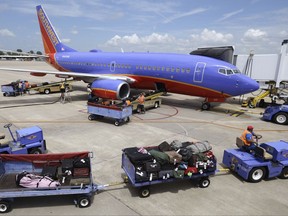 FILE - In this June 19, 2014 file photo, baggage carts are towed to a Southwest Airlines jet at Bill and Hillary Clinton National Airport in Little Rock, Ark., as the Boeing 737 is serviced. Southwest Airlines Co. reports earnings Thursday, Oct. 26, 2017. (AP Photo/Danny Johnston, File)