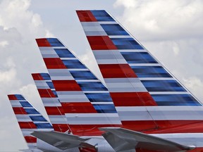 FILE - This July 17, 2015, file photo shows the tails of four American Airlines passenger planes parked at Miami International Airport, in Miami. On Thursday, Oct. 26, 2017, American Airlines Group, Inc. reports financial results. (AP Photo/Alan Diaz, File)
