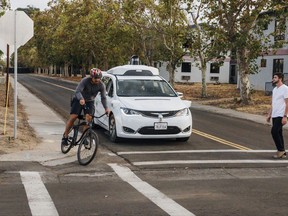 This Sunday, Oct. 29, 2017, photo provided by Waymo shows a Chrysler Pacifica minivan equipped with Waymo's self-driving car technology, being tested with the company's employees as a biker and a pedestrian at Waymo's facility in Atwater, Calif. Waymo, hatched from a Google project started eight years ago, showed off its progress Monday during a rare peek at a closely guarded testing facility located 120 miles southeast of San Francisco where its robots complete their equivalent to driver's education. (Julia Wang/Waymo via AP)