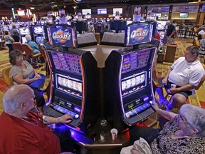 FILE – In this July 1, 2013 file photo, casino patrons play some of the 600 slot machines at the Lady Luck Casino Nemacolin, located approximately 70 miles south of Pittsburgh, shortly after its grand opening in Farmington, Pa. Pennsylvania Gov. Tom Wolf said Monday, Oct. 30, 2017, he's signed a bill authorizing a major expansion of gambling in what's already the nation's second-largest commercial casino state. The bill will make Pennsylvania the fourth state to allow online gambling, allow the state's current 10 casinos to apply for the right to operate satellite casinos, put video gambling terminals inside truck stops and allow gambling parlors in airports. (AP Photo/Gene J. Puskar, File)