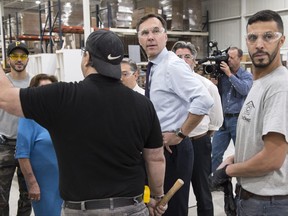Finance Minister Bill Morneau chats with workers at a kitchen counter factory, in Montreal on Tuesday, October 17, 2017. THE CANADIAN PRESS/Paul Chiasson