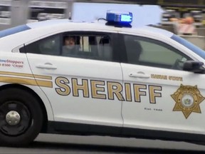 FILE - In this May 19, 2017, file image made from video provided by Hawaii News Now, Anil Uskanli is driven away from the airport in the back of a sheriff's car in Honolulu after being detained on an American Airlines flight from Los Angeles to Hawaii. Turkish man accused of causing a flight disturbance the prompted fighter jets to escort the plane to its Honolulu destination is scheduled to plead guilty Tuesday, Oct. 3. (Hawaii News Now via AP, File)