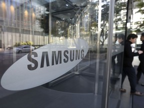 Employees walk past a logo of the Samsung Electronics Co. at its shop in Seoul, South Korea, Tuesday, Oct. 31, 2017. Samsung Electronics Co. reported another record high in quarterly earnings Tuesday as its semiconductor division posted its highest profit ever. (AP Photo/Ahn Young-joon)