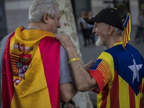 Two men, one wearing a Spanish flag, left, and the other wearing an estelada' or independence flag, talk during the celebration of a holiday known as "Dia de la Hispanidad" or Spain's National Day, in Barcelona, Spain, Thursday, Oct. 12, 2017. Spain's celebrates its national day amid one of the country's biggest crises ever as its powerful northeastern region of Catalonia threatens independence. (AP Photo/Santi Palacios)