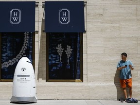 FILE - In this Friday, Aug. 18, 2017, file photo, a new security robot, nicknamed ROD2, drives toward Daniel Webb as it patrols the sidewalks and parking garage at River Oaks District in Houston. The robot recently became the latest addition to a patrol team eager to experiment with fast-evolving technology. According to a survey by the Pew Research Center, three-quarters of Americans say it is at least "somewhat realistic" that robots and computers will eventually perform most of the jobs currently done by people. Roughly the same proportion worry that such an outcome will have negative consequences, such as worsening inequality. (Michael Ciaglo/Houston Chronicle via AP, File)