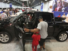 In this Monday, Oct. 9, 2017, photo, fairgoers look at pickup trucks on display at the State Fair of Texas in Dallas. America's favorite luxury vehicle is a pickup truck. Buyers are increasingly outfitting their pickups with all the comforts of luxury cars, from heated and cooled seats to backup cameras to panoramic glass roofs. (AP Photo/LM Otero)