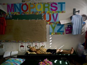 FILE - In this Oct. 13, 2017 file photo, Luis Sierra sleeps in a classroom at a school-turned-shelter after Hurricane Maria left him and other families homeless, in Toa Baja, Puerto Rico. All 1,113 public schools remain closed, though 167 have served as community centers for children and elderly people to spend part of each day and get breakfast and lunch. The education department announced that it was raising the number of campuses used in this way to 190. (AP Photo/Ramon Espinosa, File)