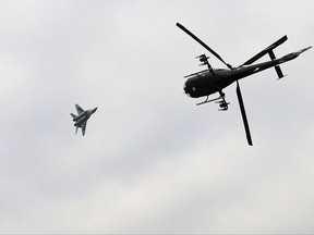 FILE - In this Feb. 13, 2010 file photo, a Serbian army Gazelle helicopter flies as a MiG 29 fighter pass overhead during exercise at a ceremony marking Statehood Day and Army Day, in Belgrade, Serbia. Russia has started the delivery of six MiG-29 fighter jets to Serbia in what could worsen tensions with neighboring states and trigger an arms race in the war-weary Balkan region. (AP Photo/Darko Vojinovic, File)