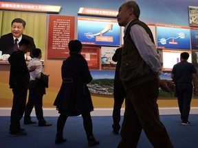Visitors walk past a chart showing China's soaring GDP since 2012 and a photo of Chinese President Xi Jinping at an exhibition highlighting China's achievements under five years of Xi's leadership at the Beijing Exhibition Hall in Beijing, China, Thursday, Oct. 19, 2017. China's economic growth stayed relatively stable in the latest quarter, buoyed by strength in retail spending and exports, giving the ruling Communist Party a boost as it prepares to appoint President Xi Jinping to a new term as leader. (AP Photo/Ng Han Guan)