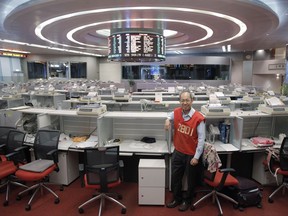 In this Oct. 19, 2017 photo, Yip Wing-keung, a trading manager at local brokerage Christfund Securities, wearing his red trading jacket, poses for a photo at the Hong Kong Stock Exchange. Hong Kong's last remaining stock market floor traders are taking their final orders as the exchange prepares to shut its trading hall, joining other world exchanges in going fully automated. (AP Photo/Kin Cheung)