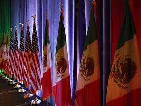 FILE - In this Aug. 16, 2017 file photo, the national flags of Canada, from left, the U.S. and Mexico, are lit by stage lights before a news conference, at the start of North American Free Trade Agreement renegotiations in Washington D.C. Mexico appears to be preparing for the worst as the fourth round of talks open in Washington D.C, Wednesday, Oct. 11, 2017.  (AP Photo/Jacquelyn Martin, File)