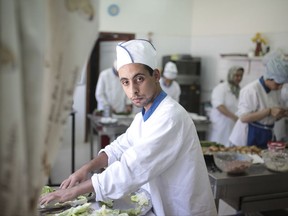 In this Tuesday, Oct. 10, 2017 photo, Saad El Saaey, 21, poses for a photo as he prepares a meal at a restaurant in Rabat, Morocco. A remarkable restaurant in Morocco's capital offers its guests the opportunity to enjoy a full, fresh meal for just $6. But what's most remarkable are its chefs: all are developmentally disabled. Since its opening in April, the restaurant has enjoyed very favorable reviews. Its customers say they appreciate the quality of the food, the low prices and the commitment behind its creation. (AP Photo/Mosa'ab Elshamy)