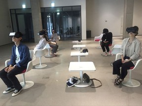 In this Sept. 14, 2017 photo, South Korean audiences wear a headset that shows "Bloodless," a virtual reality documentary about a 1992 death of a sex worker killed by an American soldier, at National Museum of Modern and Contemporary Art in Seoul, South Korea. Through a partnership of storytelling and technology, filmmaker Gina Kim finally brought the 1992 murder to life in "Bloodless," a 12-minute piece that won the award for best VR story at this year's Venice Film Festival.  (AP Photo/Youkyung Lee)