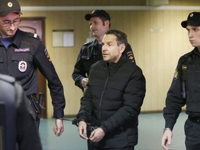 Boris Grits, 48, who holds Russian and Israeli citizenship, centre, is escorted by police officers as he arrives at a courthouse in Moscow, Russia, Tuesday, Oct. 24, 2017. The Investigative Committee has identified Boris Grits as the assailant of Tatyana Felgenhauer, a top host and deputy editor-in-chief at Russia's only independent news radio station who was stabbed at the station's studios on Monday, the latest of a string of attacks on journalists and opposition activists in Moscow. (AP Photo/Alexander Zemlianichenko)