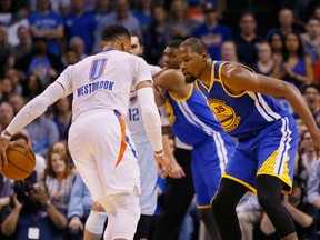 Golden State Warriors forward Kevin Durant (35) defends as Oklahoma City Thunder guard Russell Westbrook (0) dribbles during an NBA basketball game in Oklahoma City. Westbrook and Durant were teammates for years, and now are rivals.