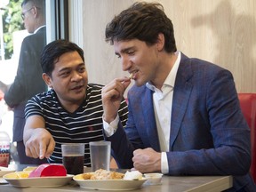 Canadian Prime Minister Justin Trudeau tries strawberry fries as he stops at a fast food restaurant in Manila, Philippines, Sunday, November 12, 2017. THE CANADIAN PRESS/Adrian Wyld
