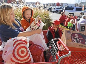 FILE - In this Friday, Nov. 24, 2017, file photo, Black Friday shoppers sort through their purchases while waiting for their rides at The Mall at Turtle Creek in Jonesboro, Ark. Americans, by most measures, appear ready to shop this holiday season. (Staci Vandagriff/The Jonesboro Sun via AP, File)