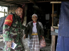 A military volunteer leads a villager during an evacuation in Karangasem, Bali, Indonesia, Thursday, Nov. 30, 2017. Authorities have told tens of thousands of people to leave an area extending 10 kilometers (6 miles) from the volcano as it belches volcanic materials into the air. Mount Agung's last major eruption in 1963 killed about 1,100 people. (AP Photo/Firdia Lisnawati)