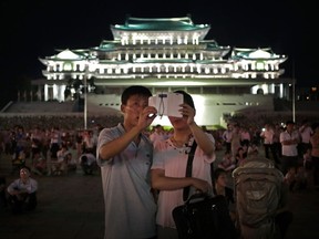 In this Sunday, July 27, 2014, file photo, a North Korean couple use a smartphone to photograph fireworks in at Kim Il Sung Square in Pyongyang, North Korea. Ever so cautiously, North Korea is going online. This is all done with a two-tiered system where the trusted elite can surf with relative freedom while the masses are kept inside the national intranet, painstakingly sealed off from the outside world and meticulously surveilled. (AP Photo/Wong Maye-E, File)