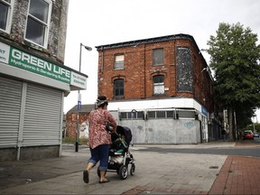 A pedestrian walks past derelict shops in Hull, United Kingdom.