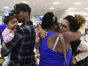 Waritza Alejandro embraces her mother-in-law Maritza Ortiz, before boarding a flight to Tampa with her husband Christian Vega and their daughter Tiana, in Carolina, Puerto Rico, Wednesday, Nov. 8, 2017. The couple lost their home to Hurricane Maria. The disaster wrought by Maria has set off an anguished debate across Puerto Rico, where friends, family and co-workers are arguing fiercely over the morality of leaving the blacked-out island vs. staying to fulfill a patriotic duty to rebuild. (AP Photo/Carlos Giusti)