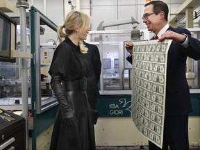 Treasury Secretary Steven Mnuchin, right, and his wife Louise Linton, left, react as Mnuchin holds up a sheet of new $1 bills, the first currency notes bearing his and U.S. Treasurer Jovita Carranza's signatures, Wednesday, Nov. 15, 2017, at the Bureau of Engraving and Printing in Washington. The Mnuchin-Carranza notes, which are a new series of 2017, 50-subject $1 notes, will be sent to the Federal Reserve to issue into circulation. (AP Photo/Jacquelyn Martin)