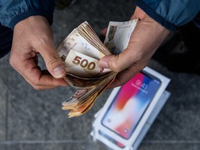 A reseller counts cash over a pile of iPhone X's near an Apple store in Hong Kong on Friday.