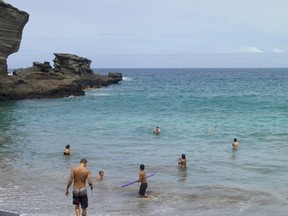 In this photo taken July 7, 2014, people sunbathe at Papakolea green sand beach near Ocean View, Hawaii. Online auction and sales company eBay has removed multiple listings of sand said to be taken from Hawaii beaches. The Hawaii Tribune-Herald reported Saturday, Nov. 4, 2017, that it asked the company about the listings before they were taken down. Among them was a listing claiming to have sand from Papakolea Beach, also known as Green Sands Beach. (AP Photo/Marco Garcia)