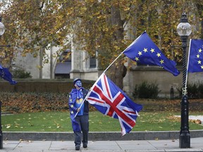 An anti Brexit, pro European Union campaigner waves flags near Parliament in London, Wednesday, Nov. 22, 2017.  Britain's Treasury chief has little room to maneuver Wednesday as he reveals his spending plans to a nation bracing for the shock of Brexit. While Philip Hammond is promising to tackle a bleak economic outlook "head on," a slowing economy and stubborn deficit mean there is little money available to increase spending in the face of demands from teachers, firefighters, the National Health Service and the military.  (AP Photo/Kirsty Wigglesworth)