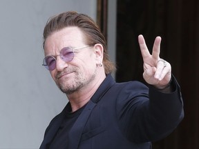 FILE - In this Monday, July 24, 2017 file photo, U2 singer Bono makes a peace sign as he arrives for a meeting at the Elysee Palace, in Paris, France. Leaked papers revealing investments in tax havens by the world's wealthy suggest U2 frontman Bono used a company based in low-tax Malta to buy part of a shopping mall in Lithuania, it was announced on Monday Nov. 6. (AP Photo/Michel Euler, file)