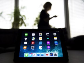 A woman uses her smart phone as apps are shown on an iPad in Mississauga, Ont., on Monday, November 13, 2017. For the roughly 8,000 Canadians who had personal data stolen by hackers in the massive Equifax data breach earlier this year, trust and peace of mind are now difficult to come by. THE CANADIAN PRESS/Nathan Denette