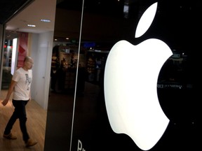 FILE - In this Monday, Nov. 16, 2015, file photo, a man walks into one of Apple's authorized premium resellers' outlets in Singapore. Apple revamped its overseas subsidiaries to take advantage of tax loopholes on the European island of Jersey after a crackdown on Ireland's loose rules began in 2013, according to The New York Times and the International Consortium of Investigative Journalists. (AP Photo/Wong Maye-E, File)