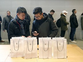 FILE - In this Friday, Nov. 3, 2017, file photo, Jiahao Luo, left, and Jiahao Wang, from China, configure one of the four new Apple iPhone X's they purchased at the new Apple Michigan Avenue store along the Chicago River in Chicago. On Wednesday, Nov. 15, 2017, the Commerce Department releases U.S. retail sales data for October. (AP Photo/Charles Rex Arbogast, File)