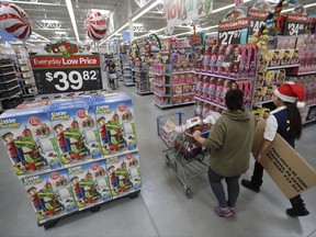 FILE - In this Wednesday, Oct. 26, 2016, file photo, a shopper, left, walks with a store associate in the toy section at Walmart in Teterboro, N.J. As more shoppers shift online, Walmart hopes to make its stores more fun this holiday season. The chain will have parties for customers at its stores for the first time, increase the number of product demonstrations and expand the role of employees who last year helped people find the shortest register lines. Many retailers are trying to make stores more inviting even as they improve online services. (AP Photo/Julio Cortez, File)