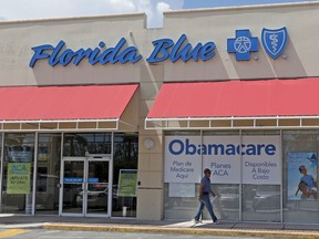 FILE - In this Thursday, July 27, 2017, file photo, a person walks by a health care insurance office in Hialeah, Fla. Health insurance shoppers will face a new deadline, rising prices and fewer options for help in many markets when the Affordable Care Act's main enrollment window for 2018 coverage opens Wednesday, Nov. 1. Insurance experts say those who need insurance should avoid waiting to do last-minute shopping. (AP Photo/Alan Diaz, File)