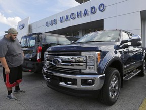 FILE - In this Tuesday, Jan. 17, 2017, file photo, a potential customer looks at a Ford F-250 Lariat FX4 at a Ford dealership, in Hialeah, Fla. Ford posted a big sales jump in October 2017 but Fiat Chrysler and General Motors reported declines as auto companies started to report numbers Wednesday, Nov. 1. The drop by two of the Detroit Three backs analysts' expectations that September's big gain in U.S. auto sales would fizzle in October. (AP Photo/Alan Diaz, File)