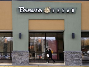 FILE - In this Wednesday, April 12, 2017, file photo, a passer-by walks near an entrance to a Panera Bread restaurant in Natick, Mass. In a deal announced Wednesday, Nov. 8, 2017, Panera Bread says it is buying bakery chain Au Bon Pain to boost its presence in airports, hospitals and colleges. (AP Photo/Steven Senne, File)