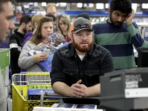 FILE - In this Thursday, Nov. 23, 2017, file photo, people line up to check out as they shop a Black Friday sale at a Best Buy store on Thanksgiving Day, in Overland Park, Kan. On Thursday, Nov. 30, 2017, the Commerce Department issues its October report on consumer spending, which accounts for roughly 70 percent of U.S. economic activity. (AP Photo/Charlie Riedel, File)