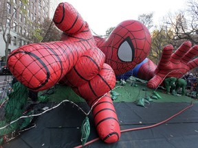 FILE - In this Nov. 21, 2012 file photo, workers inflate the Spider-Man balloon for the annual Macy's Thanksgiving Day Parade in New York. New York police say the Macy's Thanksgiving Day Parade balloon inflation viewing will end two hours early this year and anyone attending must be screened. Tens of thousands of people are expected to head to Central Park on Wednesday to watch the giant balloons take shape. (AP Photo/Richard Drew, File)