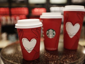 This photo shows Starbucks' cups with a new design at a Starbucks coffee shop in New York on Monday, Nov. 27, 2017. If this year's Starbucks holiday cup wasn't red enough, the chain is releasing another one this week that's mostly that color. The new cup, in stores for a limited time, has a white heart in the middle and an illustration of two hands making a heart shape. (AP Photo/Hiro Komae)