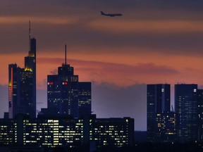 An aircraft passes over the banking district as it approaches the airport in Frankfurt, Germany, early Monday, Nov. 27, 2017. (AP Photo/Michael Probst)