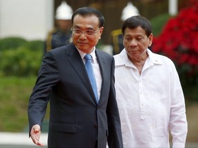 FILE - In this Nov. 15, 2017 file photo, Chinese Premier Li Keqiang, left, gestures to Philippine President Rodrigo Duterte as they prepare for their bilateral meeting following a welcome ceremony at Malacanang Palace grounds in Manila, Philippines.  President Duterte has offered to China an opportunity to operate a new, third telecommunications carrier in the country, his spokesman said Monday, Nov. 20, 2017.  The move is aimed at breaking a telecoms duopoly in a country that is said to have the slowest internet speed in the Asia Pacific. It is unclear if China or any Chinese companies would be keen to take Duterte up on his offer. Presidential spokesman Harry Roque said Duterte made the offer to Chinese Premier Li during their bilateral meeting in Manila last week.(AP Photo/Bullit Marquez, File)