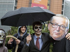 A demonstrator with a mask of European Commission President Jean-Claude Juncker, right, and another with facepaint pose in front of EU headquarters to highlight the glyphosate issue in front of EU headquarters in Brussels, Monday, Nov. 27, 2017. European Union nations will again assess on Monday whether they should continue to use of one of the world's most widely used weed killers, glyphosate, amid concerns about its possible links to cancer. (AP Photo/Virginia Mayo)