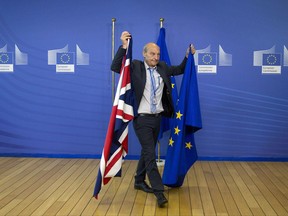 FILE - In this June 19, 2017 file photo, a member of protocol changes the EU and British flags at EU headquarters in Brussels. The European Union is resuming negotiations with Britain, Thursday, Nov. 9, 2017, on its departure from the 28-nation bloc amid more warnings that time is running out to reach an agreement before Brexit in March 2019. (AP Photo/Virginia Mayo, File)