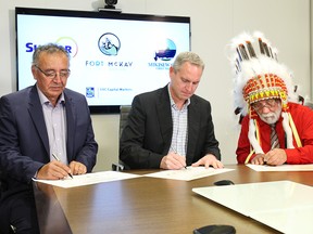 Chief Jim Boucher of Fort McKay First Nation, left, Mark Little, president, Upstream with Suncor, centre, and Chief Archie Waquan of Mikisew Cree First Nation sign a certificate of closing at a ceremony in Calgary on Nov. 22