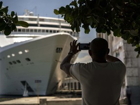 FILE - In this June 17, 2017, file photo, a man takes a photo of a cruise ship in Havana harbor, Cuba. President Donald Trump announced a new policy in June that partially rolled back the recent diplomatic opening with Cuba. New regulations implementing that policy are being unveiled Wednesday.  (AP Photo/Ramon Espinosa, File)