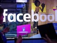 In this April 18, 2017, file photo, conference workers speak in front of a demo booth at Facebook's annual F8 developer conference, in San Jose, Calif.